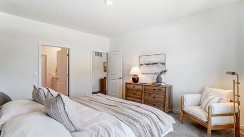 primary bedroom bed, dresser, accent chair and ensuite bath