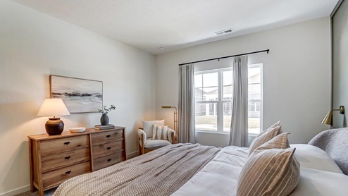 primary bedroom bed, dresser and accent chair