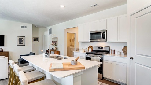 built in island with barstools, white cabinets, stainless steel appliances and corner walk in pantry
