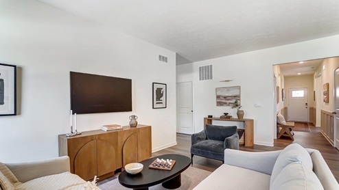 furnished great room with sectional, chair, credenza, tv, entry way