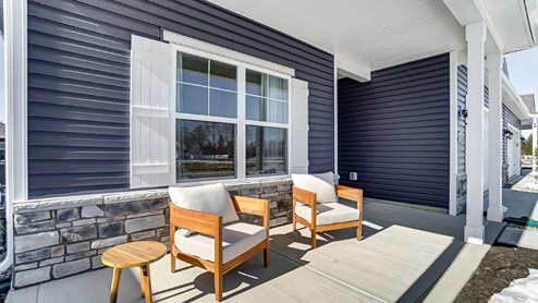 two outdoor chairs and side table on front porch