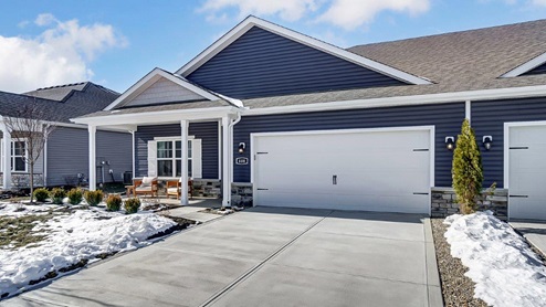 single-story attached home with blue siding, covered front porch with seating, two car garage