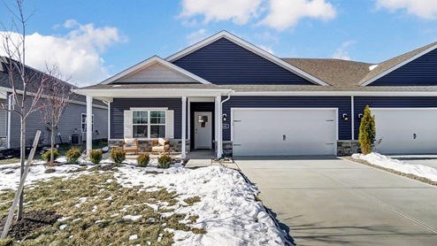 single-story attached home with blue siding, covered front porch with seating, two car garage