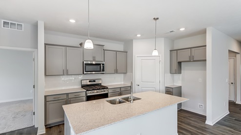 kitchen with grey cabinets, built in island with pendant lights, stainless steel appliances, corner walk in pantry