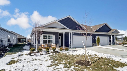 single story home with blue siding, covered front porch with chairs, two car garage