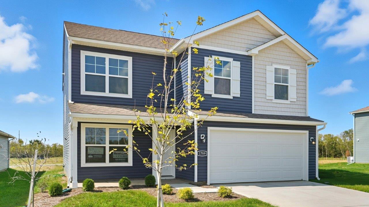 Two story home with blue and grey siding, covered front porch and two car garage