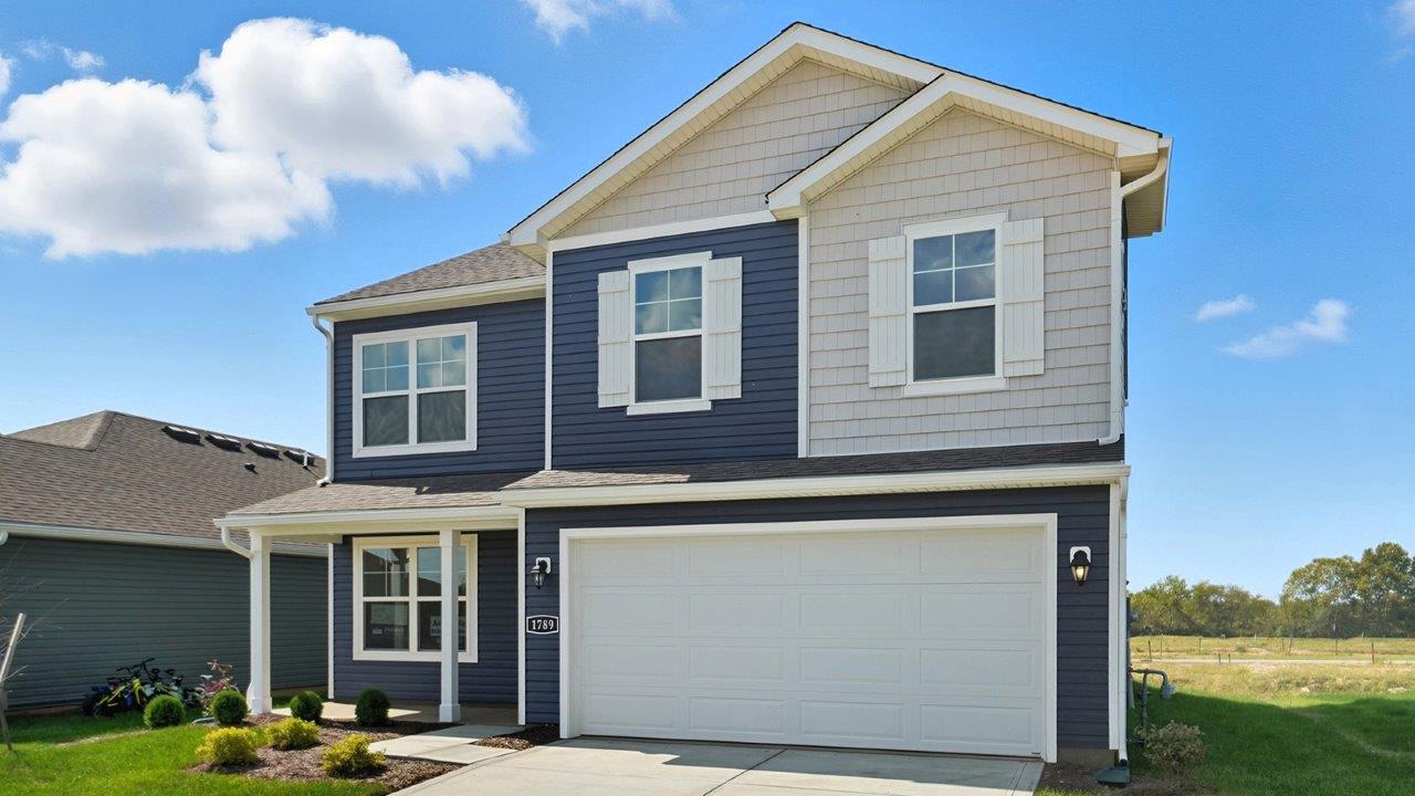 Two story home with blue and grey siding, covered front porch and two car garage