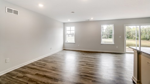 great room with white walls and vinyl flooring