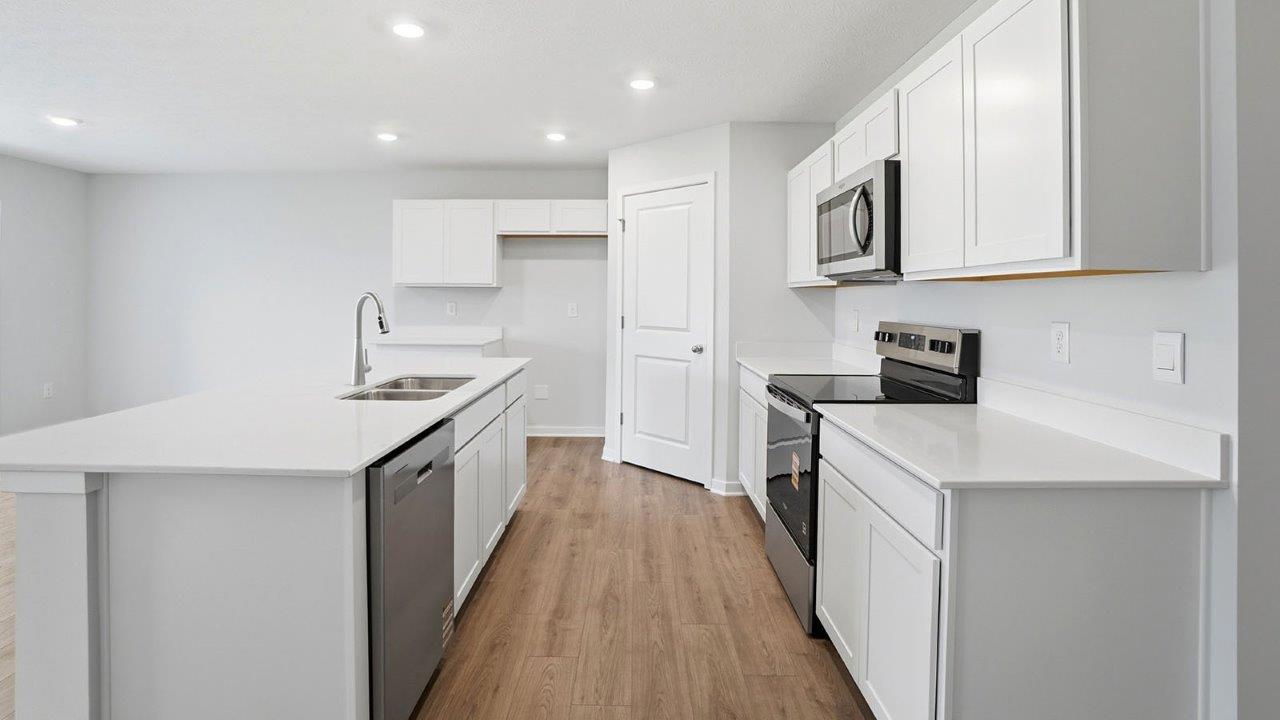 kitchen with built in island, white cabinets, corner walk in pantry, stainless steel appliances