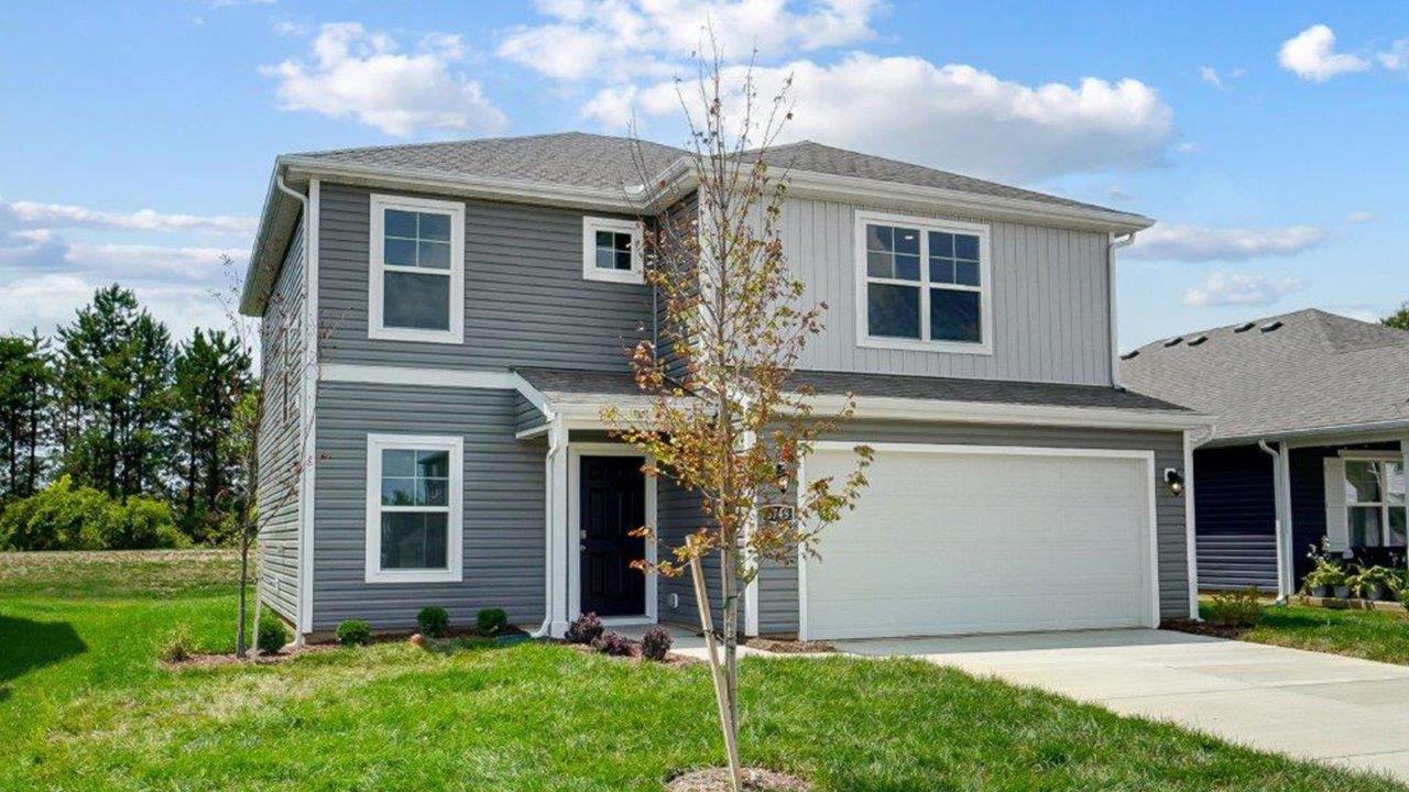 two story home with grey siding, covered entry, two car garage