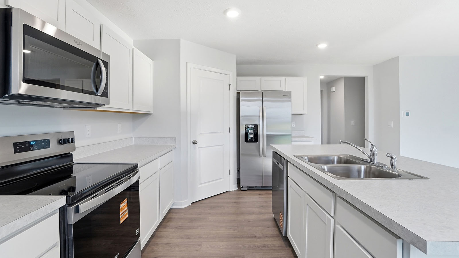 kitchen with white cabinets, stainless steel appliances, built in island and corner walk in pantry