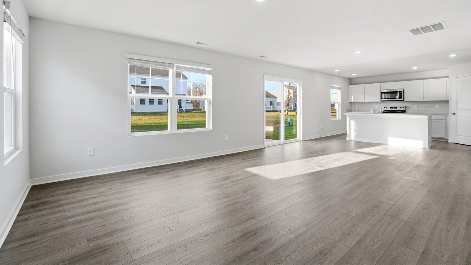 great room with two windows, rear sliding door and kitchen