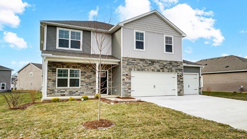 two story home with grey siding, partial stone front, covered front porch and three car garage