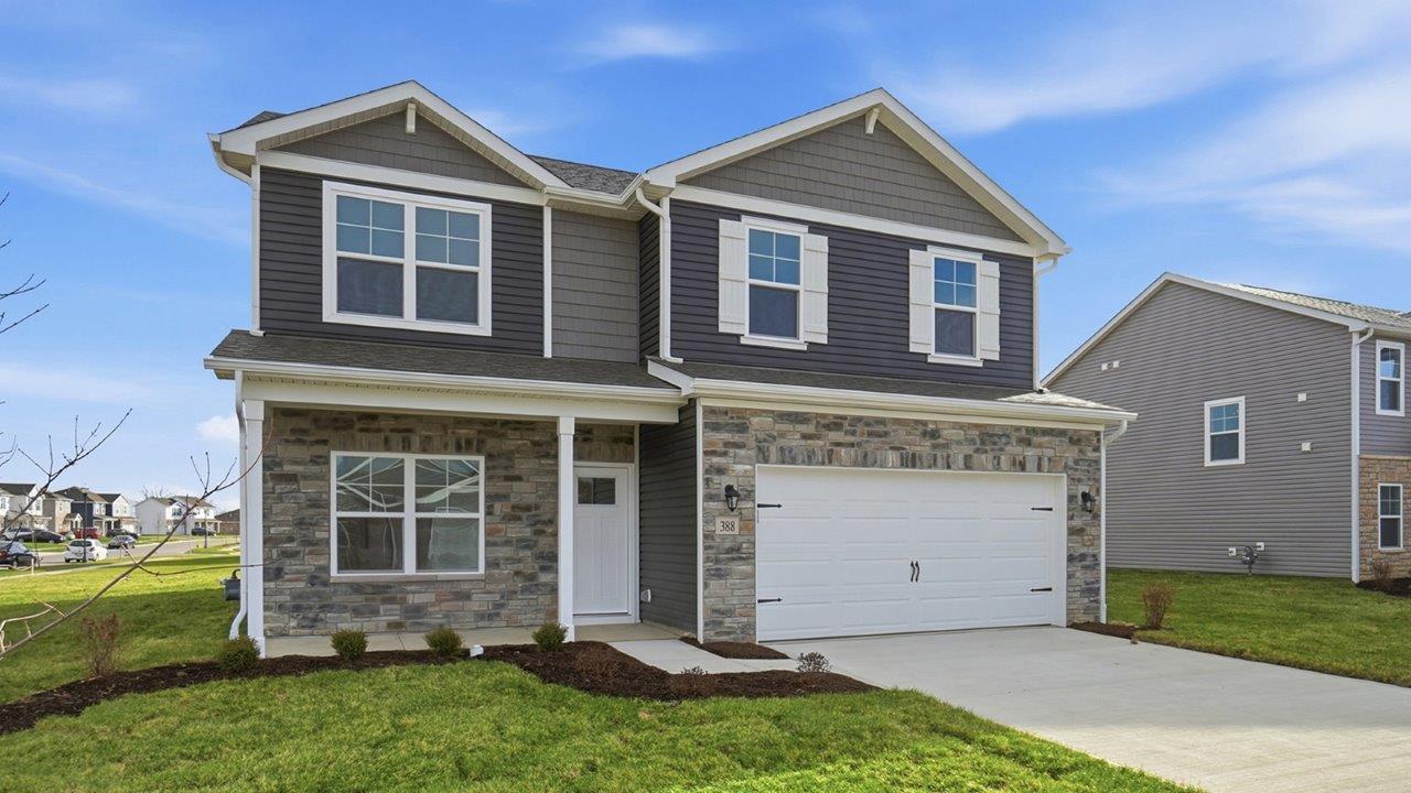 Two story home with grey siding, partial stone front, covered front porch and two car garage