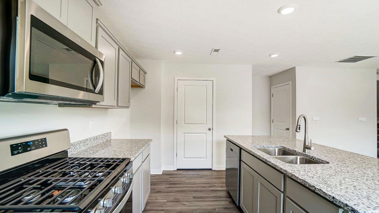 kitchen with grey cabinets, built in island, stainless steel appliances, walk in pantry
