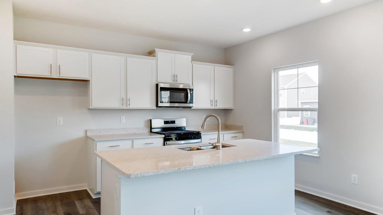 kitchen with white cabinets, built in island, stainless steel appliances and single window