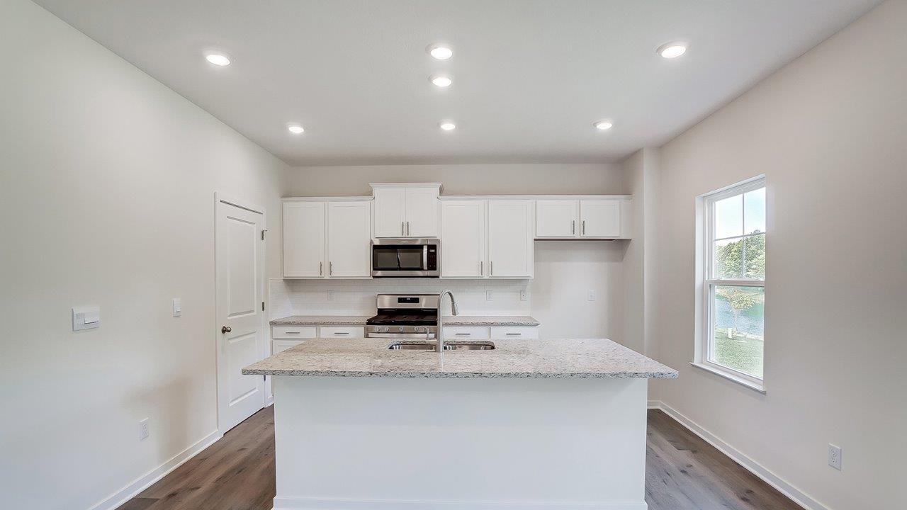 kitchen with white cabinets, built in island, stainless steel appliances, walk in pantry