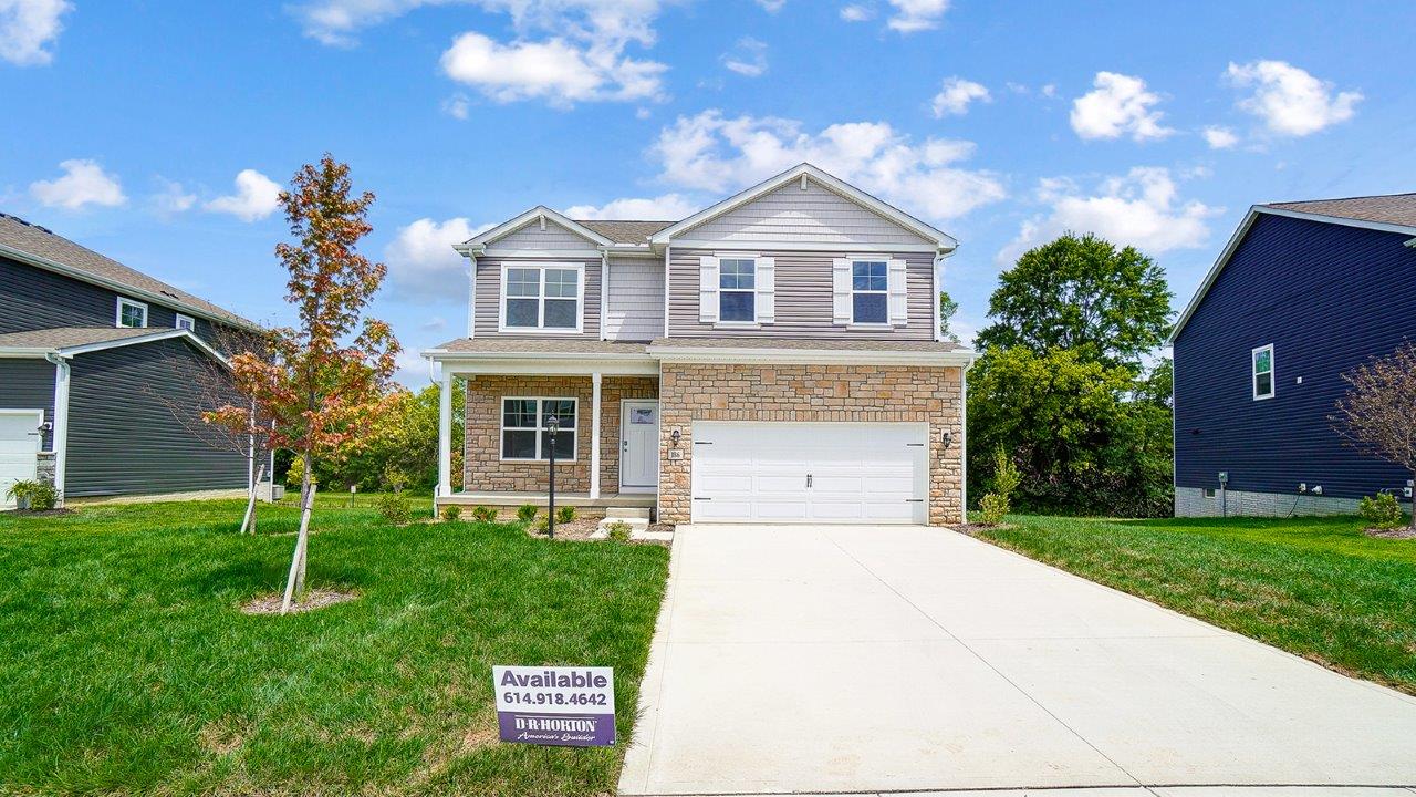 two story home with tan siding, partial stone front, covered front porch and two car garage