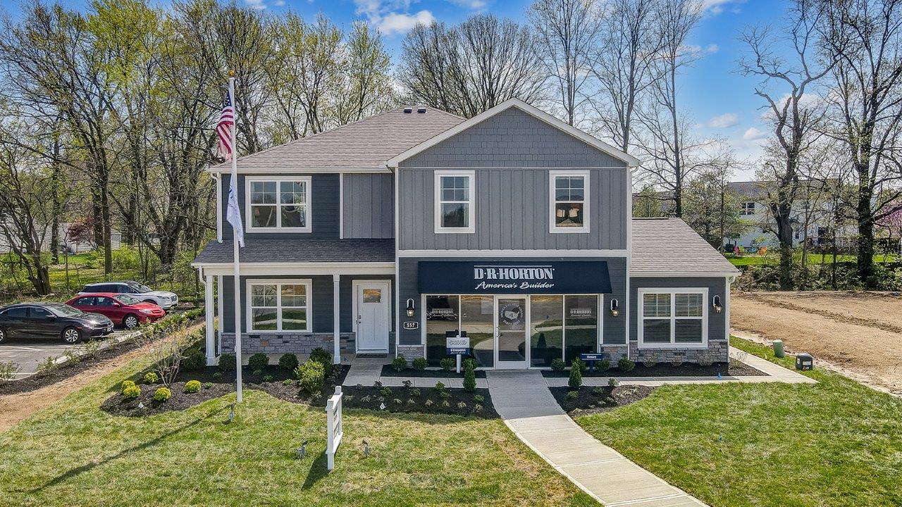 two story model home with grey siding, covered front porch and three car garage storefront