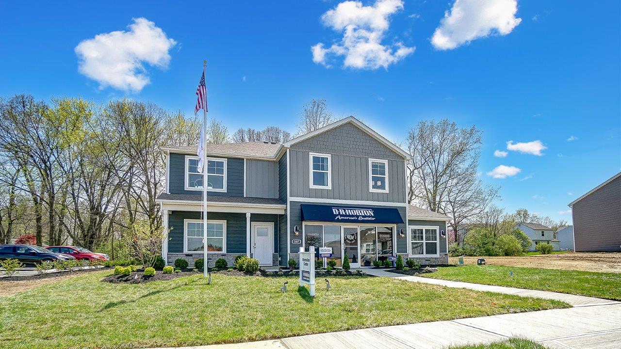 two story model home with grey siding, covered front porch and three car garage storefront