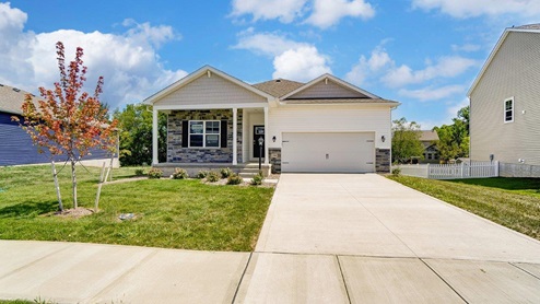 single story home with grey and white siding, partial stone front, covered front porch, two car garage
