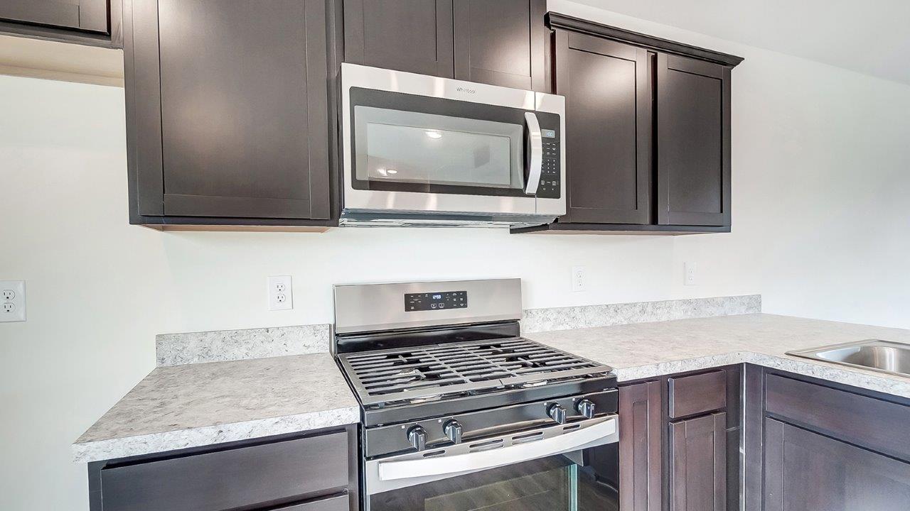 brown kitchen cabinets, stainless steel range and microwave