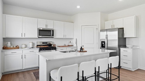 kitchen with white cabinets, built in island, corner walk in pantry, stainless steel appliances