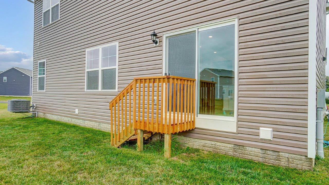 Backyard deck offering access for outside seating, grill setup, and a transition from indoor to outdoor living