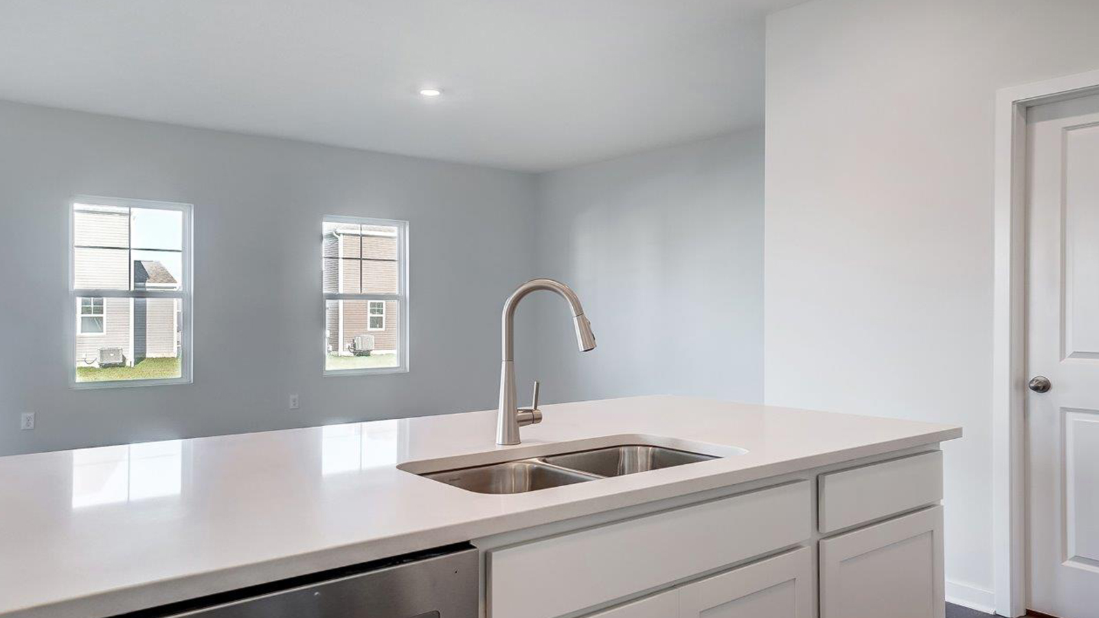 Kitchen island in D.R. Horton layout connects dining, main living areas, and outside with efficient flow and modern designs