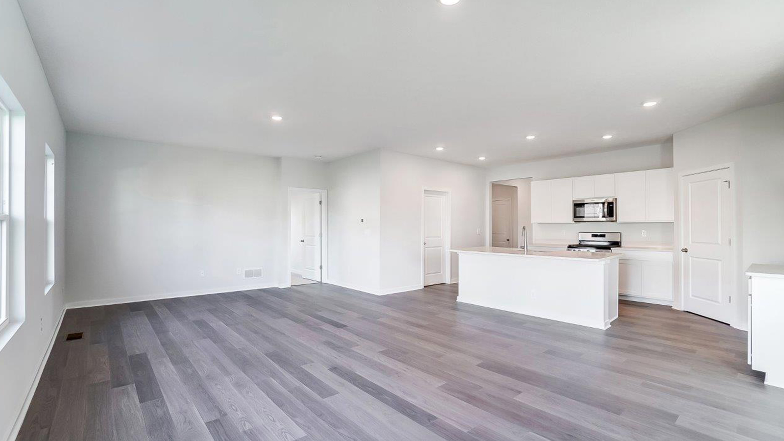 Living room looking to dining and kitchen areas in this new home features natural light, with fresh open concept flow
