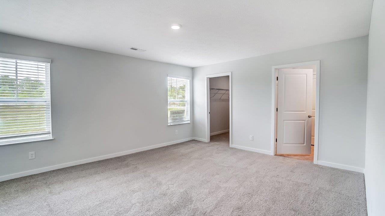 Bedroom with an ensuite bathroom with two single windows and a closet.