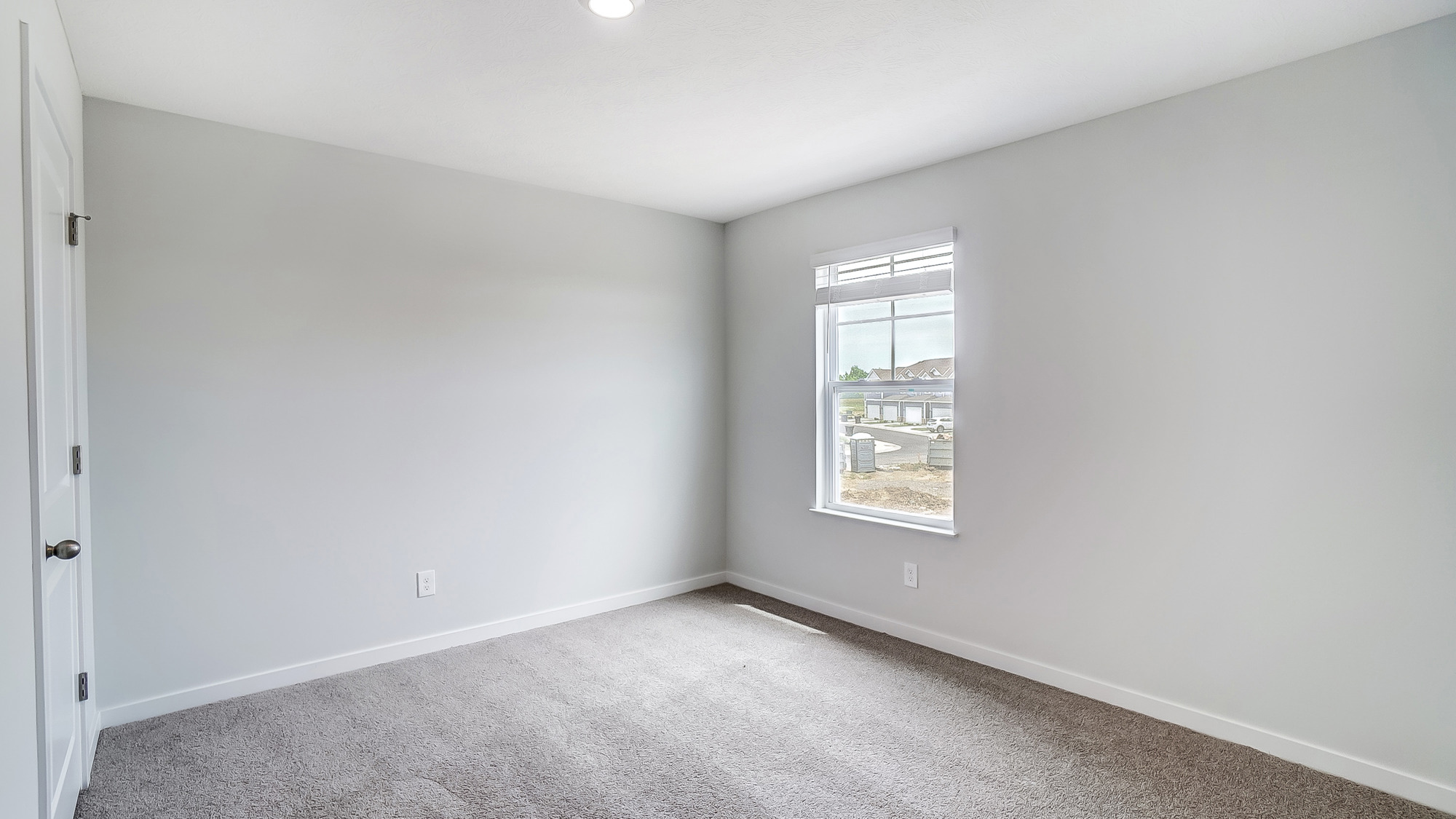 Carpeted bedroom with a single window.