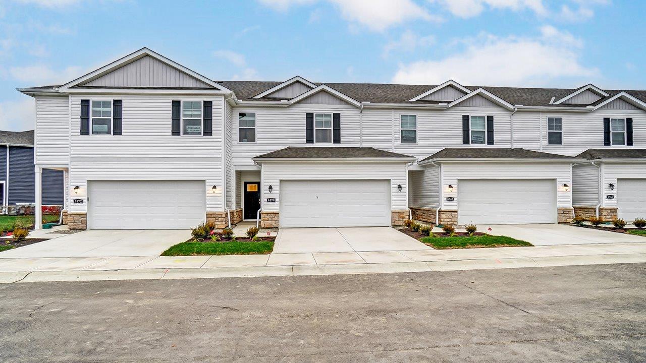 four-unit two story townhome building with white siding and two car garages