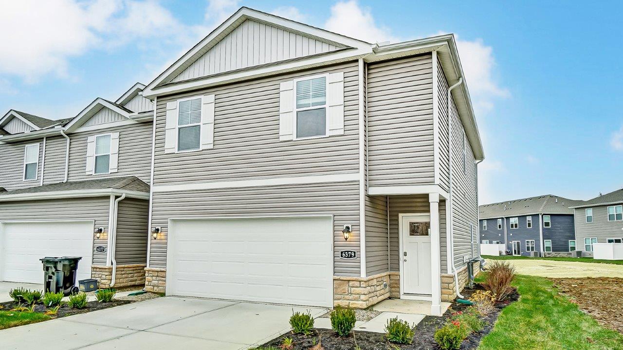 Exterior two story townhome unit with grey siding and two car garage
