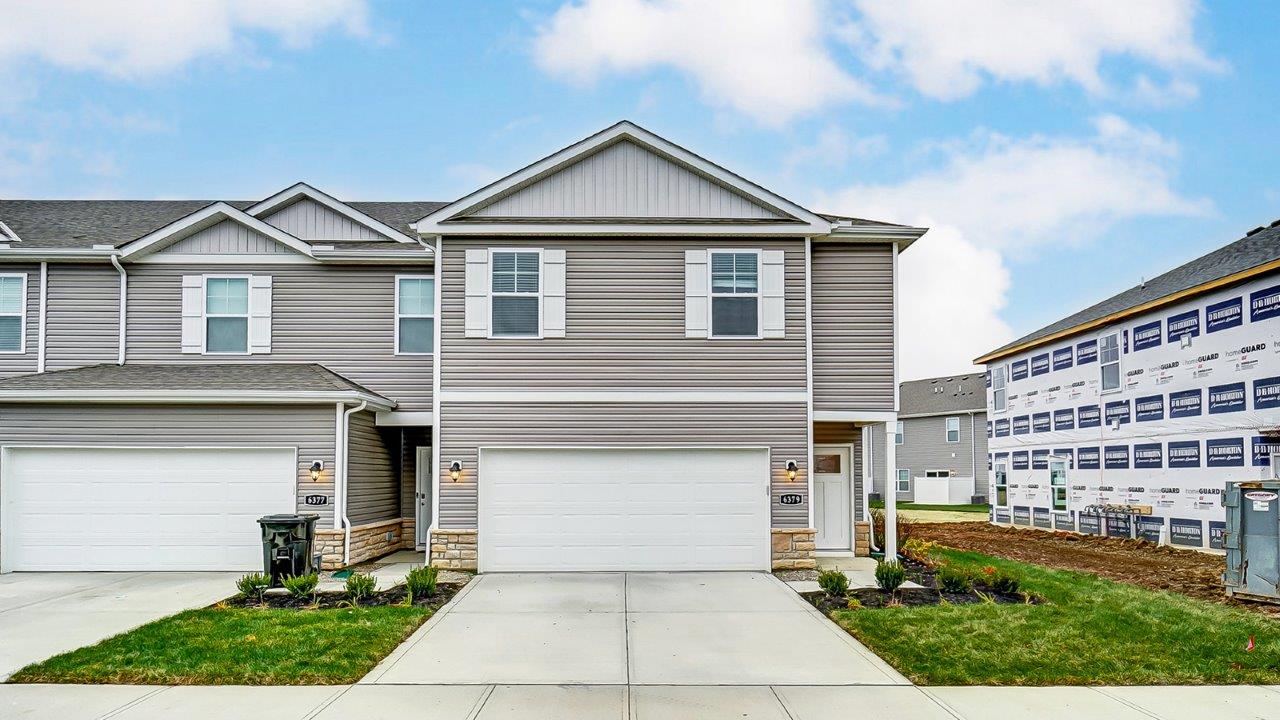 Exterior two story townhome unit with grey siding and two car garage