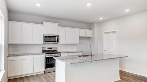kitchen with white cabinets, built in island, stainless steel appliances, walk in pantry