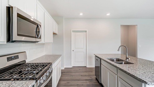 white kitchen cabinets, stainless steel appliances, built in island and walk in pantry
