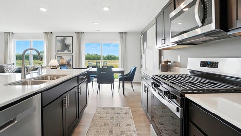 kitchen with brown cabinets, hard surface counters, stainless steel appliances and dining area