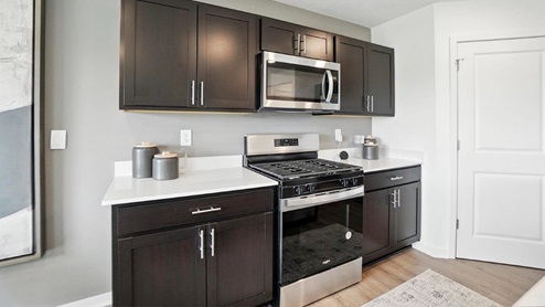brown kitchen cabinets, hard surface counters, corner walk in pantry, stainless steel appliances