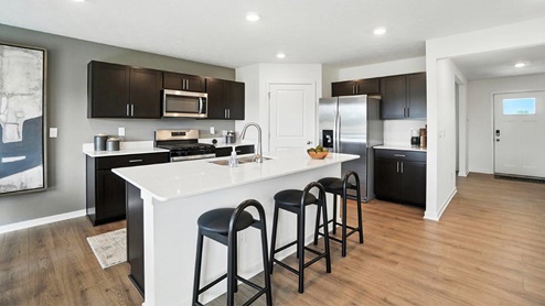 kitchen with island and barstools, brown cabinets and walk in corner pantry