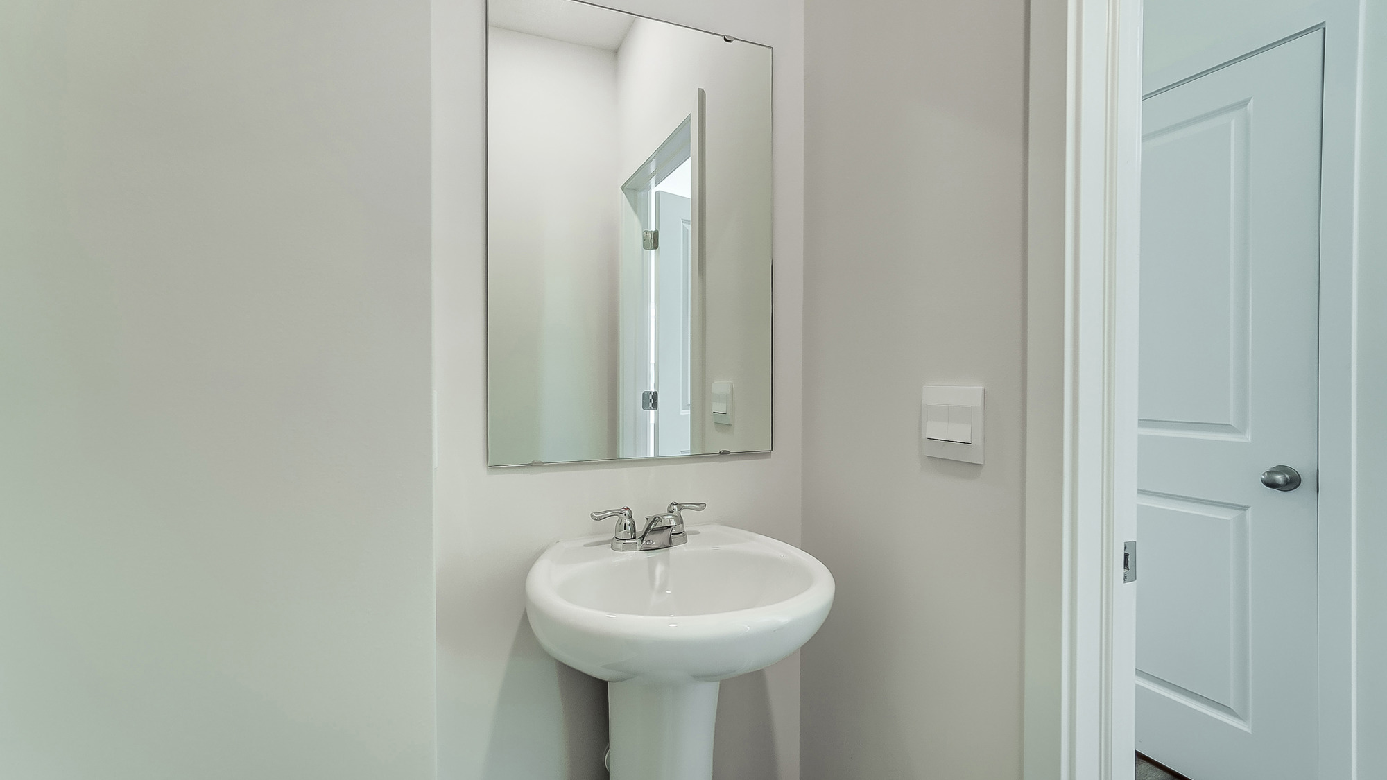 Powder bathroom with a pedestal sink and mirror