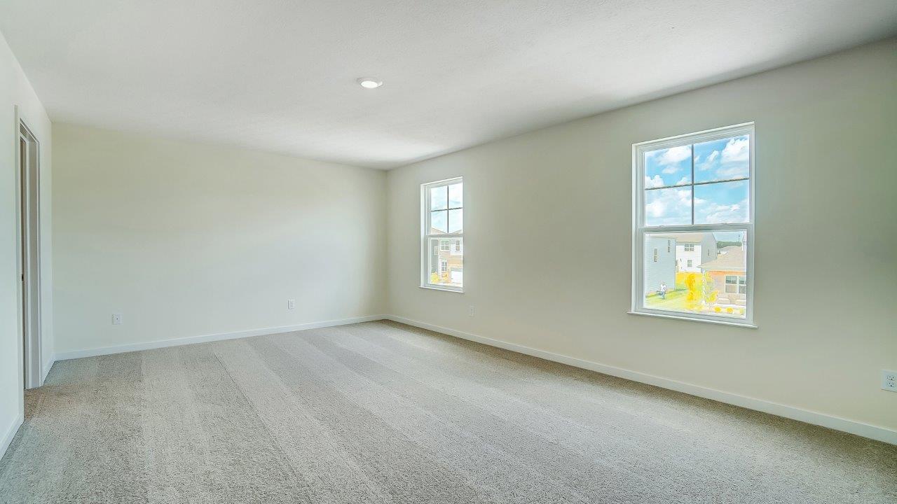 bedroom with beige carpet, white walls and a window