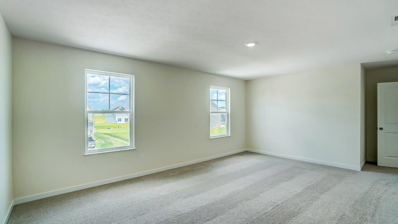bedroom with beige carpet, white walls and a window
