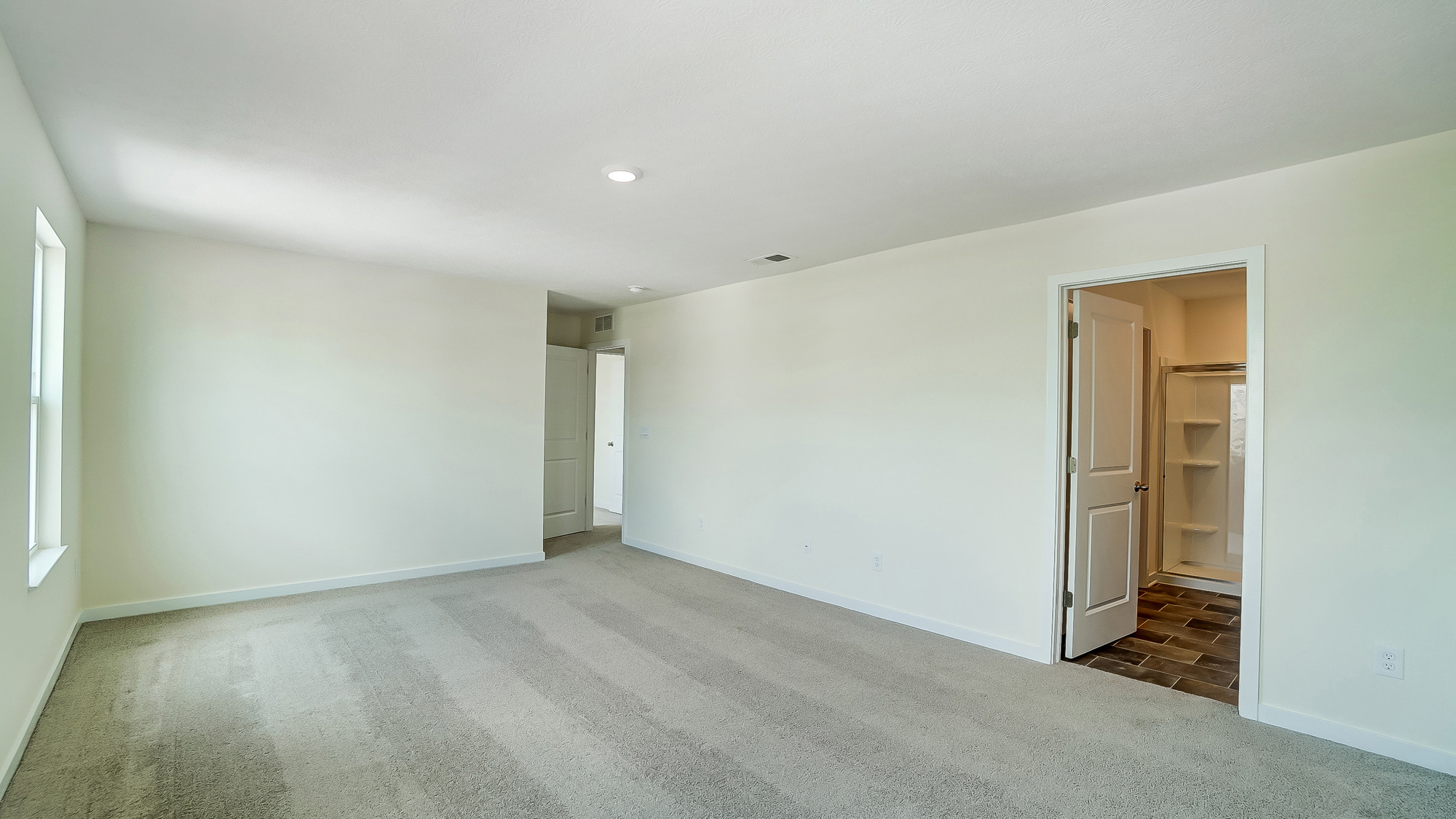 bedroom with beige carpet, white walls and a window