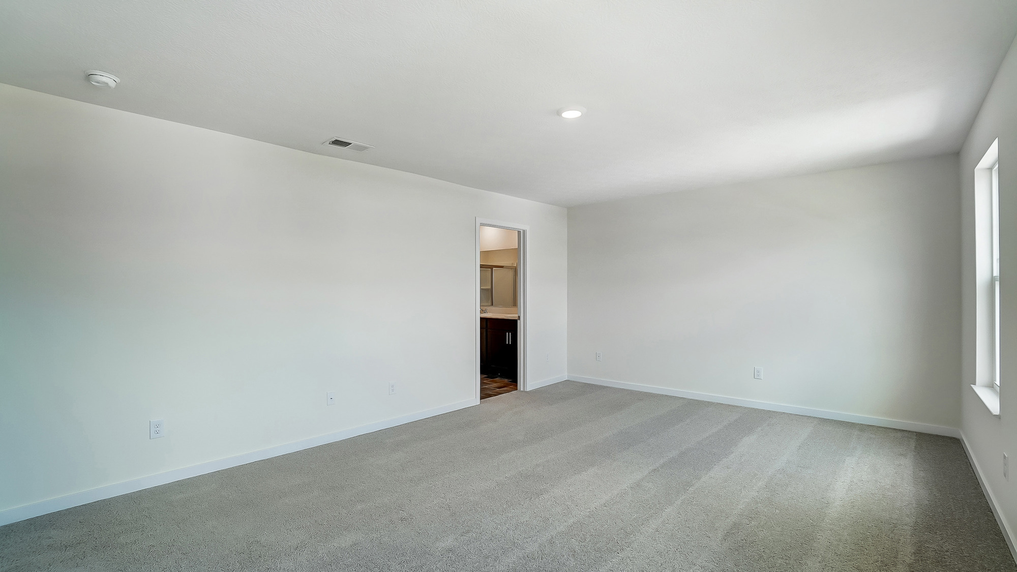bedroom with beige carpet, white walls and a window