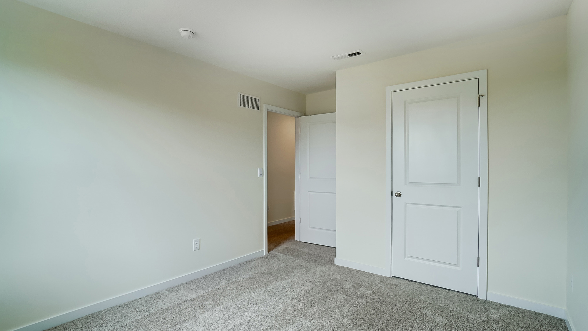 bedroom with beige carpet, white walls and a window