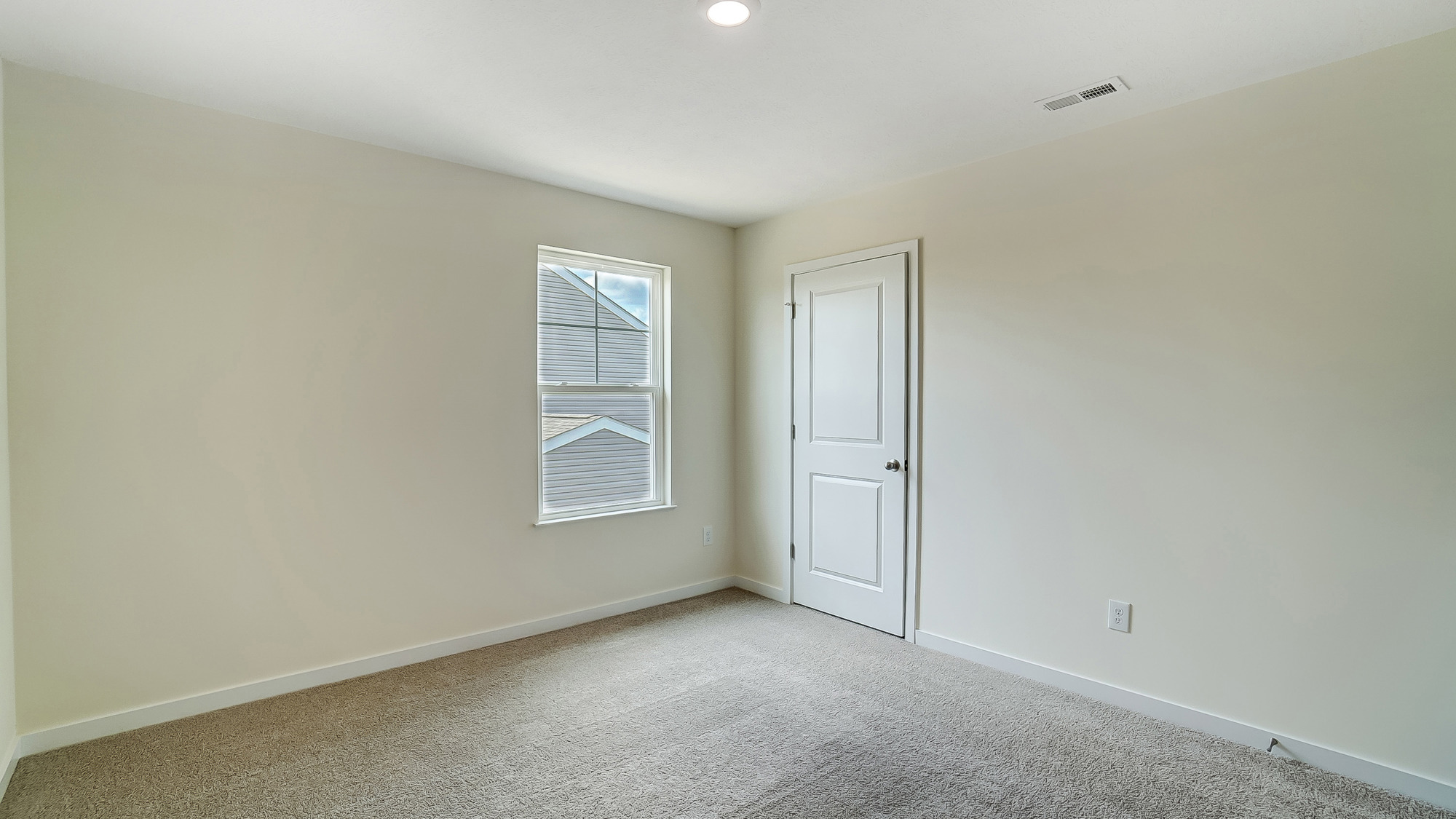bedroom with beige carpet, white walls and a window