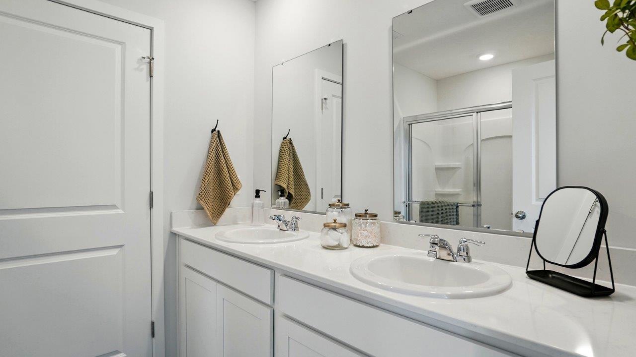 bathroom with dual vanity sinks, toilet, and a walk in shower