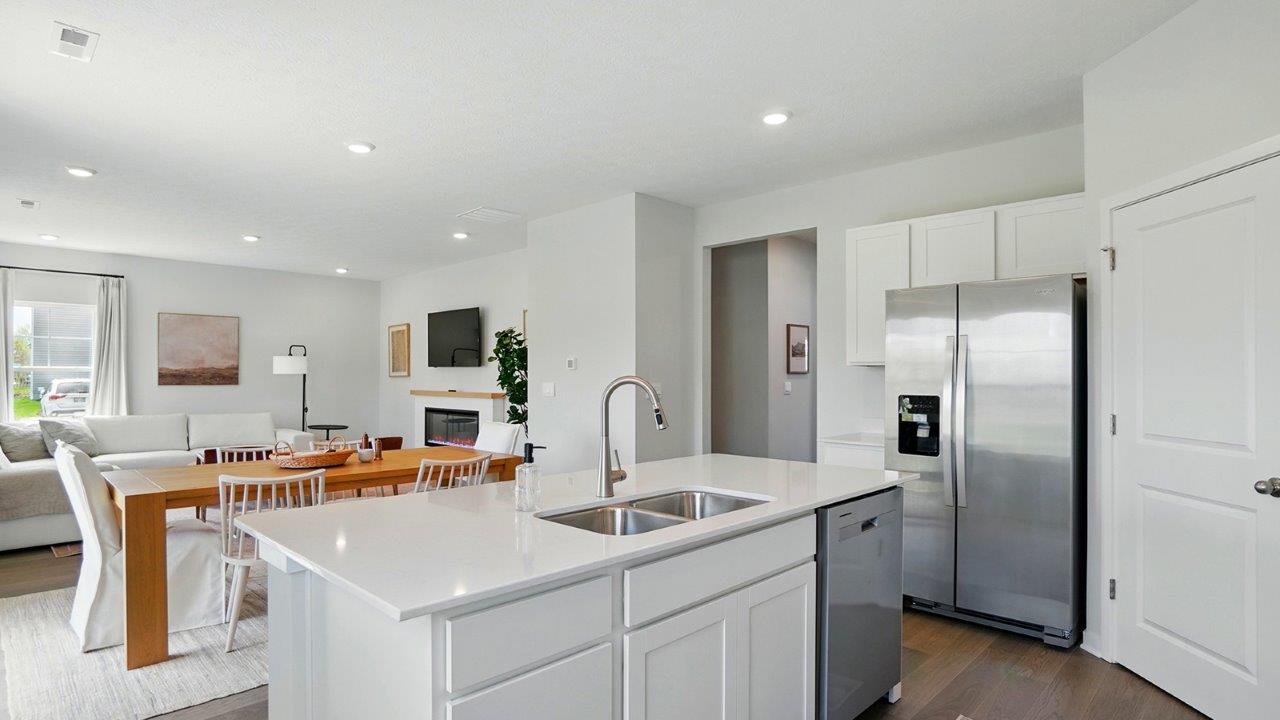 spacious modern kitchen featuring white cabinetry, large island and stainless steel appliances