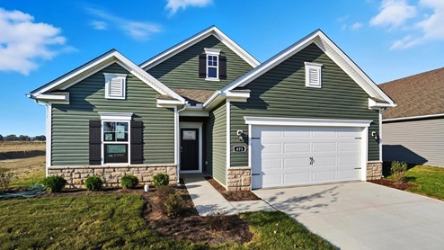 Single story home with green siding, stone water table and two car garage